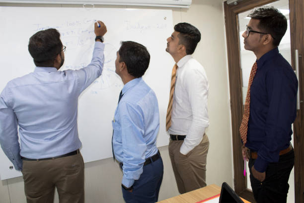 istock Four male colleagues discussing new business plan on office whiteboard 1185217262