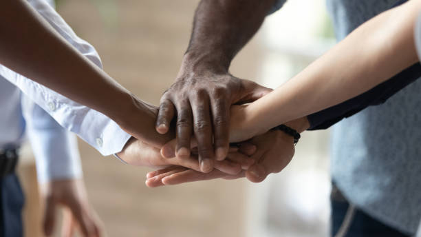istock Close up image multiracial people joining hands demonstrating unity. 1185220771