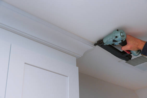 istock Carpenter nailing crown moldings in the kitchen cabinets framing trim worker using brad nail gun 1185222393