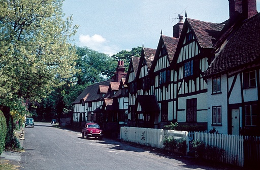 England, UK, 1962. Old English village street with half timbered houses and parked cars.