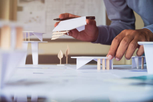 istock architect design working drawing sketch plans blueprints and making architectural construction model in architect studio 1185226396