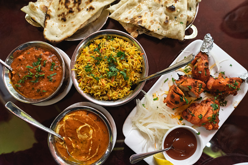 Assortment of Indian dishes for dinner, butter chicken, tikka masala, basmati rice and naan
