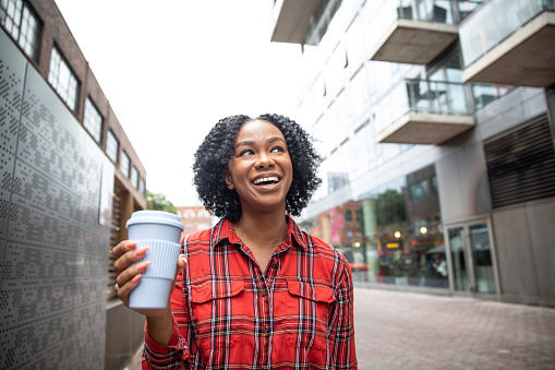 happy black woman holding a reusable plastic coffee cup