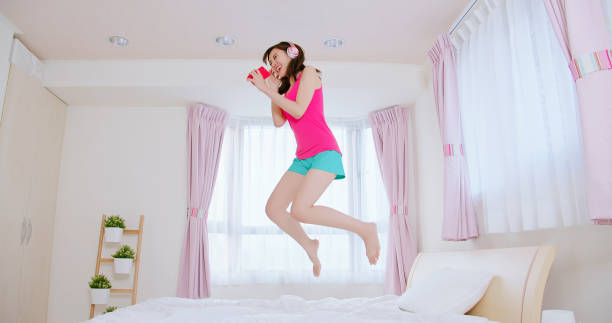 istock Young woman jump on bed 1185229333