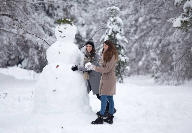 istock Girls building snowman in park 1185231800