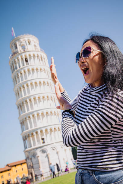 이탈리아 피사의 유명한 사탑 앞에서 재미있는 포즈를 취하는 아시아 여성 여행자. 이탈리아 컨셉의 행복한 여행 사진 - pisa cathedral 뉴스 사진 이미지