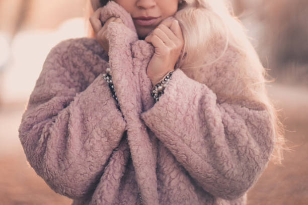 Girl wearing warm winter coat outdoors Beautiful woman wearing cozy pink fur coat outdoors over sunny background in city. Winter season. winter coat stock pictures, royalty-free photos & images