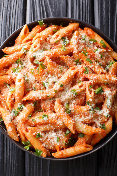 istock Penne alla vodka is a pasta dish made with vodka, usually made with heavy cream, crushed tomatoes, onions close-up on the table. Vertical top view 1185235168