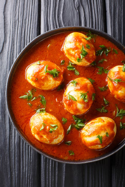 istock Boiled curry eggs in spicy sauce close-up in a plate. Vertical top view 1185235293