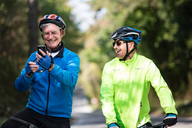 Smiling Senior Men Cycling Friends Using Mobile Phone