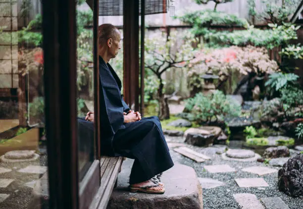 Japanese man meditating in his garden
