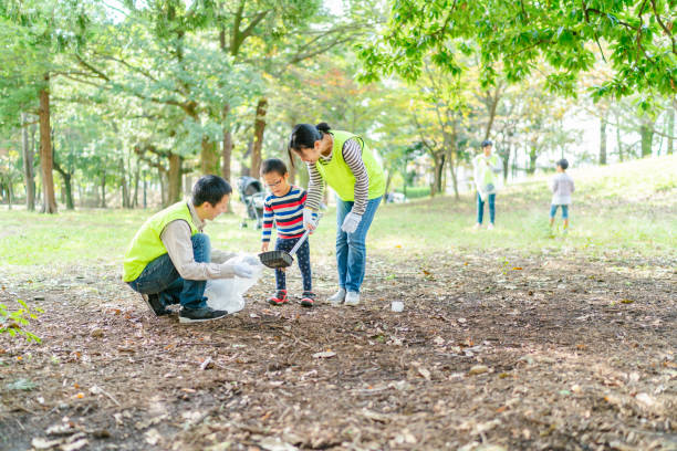 Family volunteering clening up public park A family is volunteering cleaning up a public park with their small son who has Down syndrome. child japanese culture japan asian ethnicity stock pictures, royalty-free photos & images