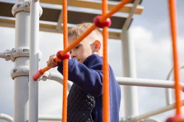 A little boy climbs the cable ladder. stock photo