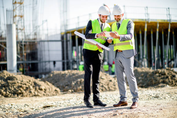 istock Young and senior engineer holding blueprint and tablet on construction site 1185240883