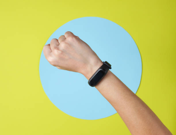 istock Smart bracelet on hand wrist on green background with blue circle. Top view 1185242008