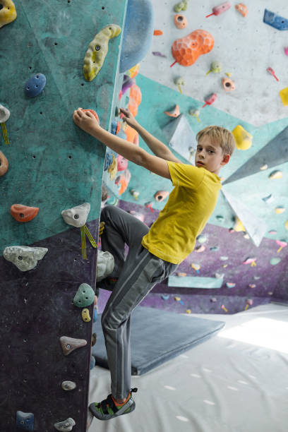 boy in sportswear looking at you while holding by small rocks and climbing - small gymnastics athlete action imagens e fotografias de stock