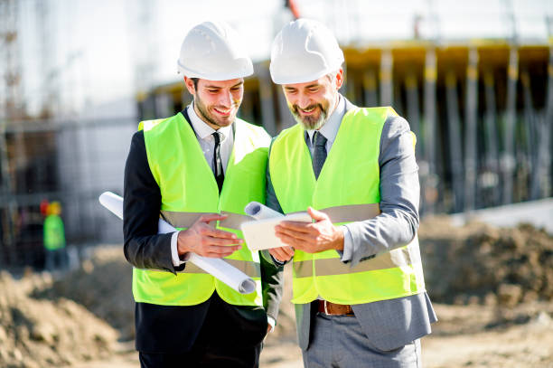 istock Young and senior engineer holding blueprint and tablet on construction site 1185243269