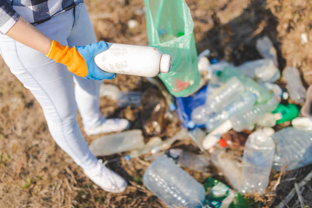 close up of woman hand collecting plastic garbage bottle from the ground. recycling and ecology concept. - polyethylene terephthalate imagens e fotografias de stock