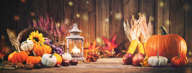 Pumpkins with fruits and falling leaves on rustic wooden table