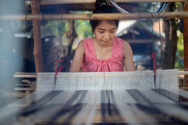 istock Young women weaving with traditional Thai weaving machine 1185245648