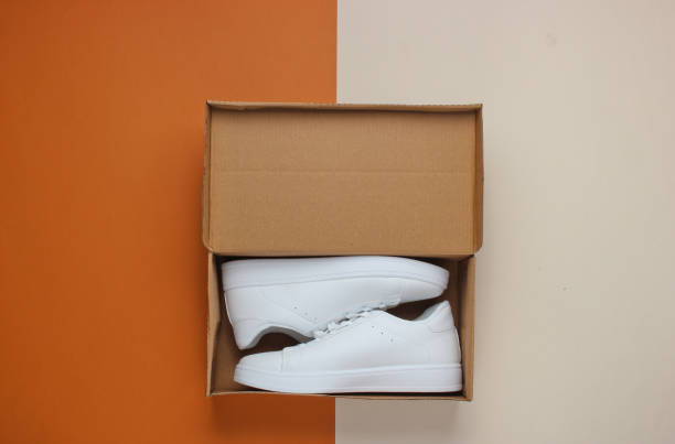 istock New white sneakers in box on two-ton paper background. Top view 1185249717