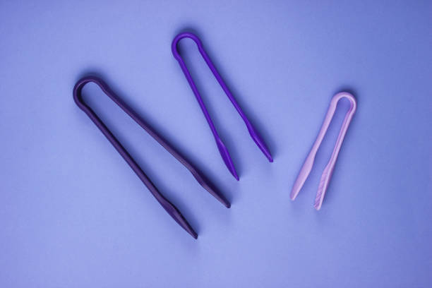 istock Kitchen tongs on purple paper background. Top view 1185250263