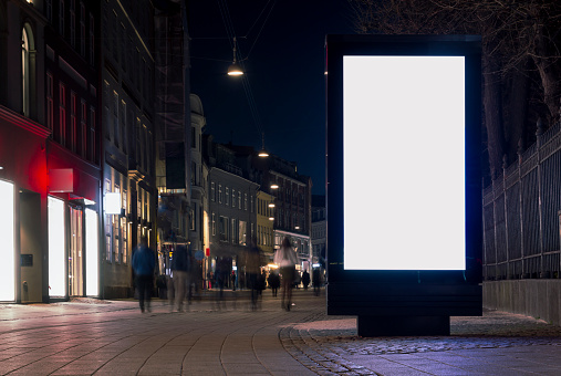 Blank advertisement billboard, with blurred people at night