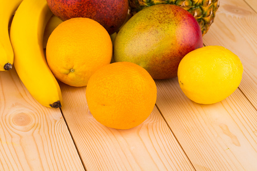 Still life with citrus fruits and mango. All this is located on wooden surface. Close-up.