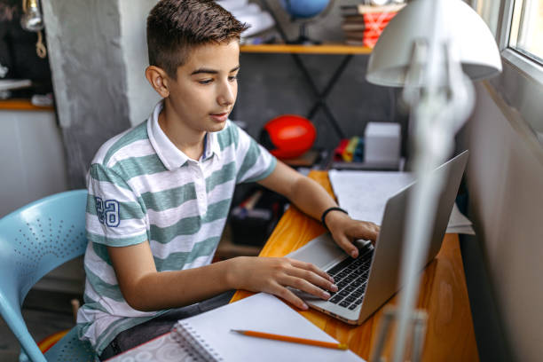 Teenage boy doing homework on laptop