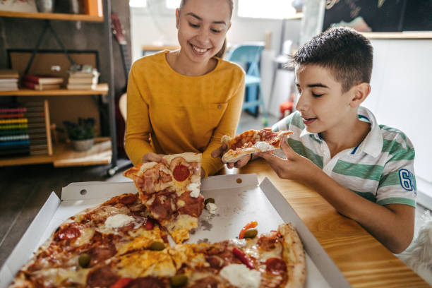 istock View of happy siblings eating pizza 1185253648