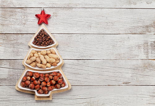 Christmas greeting card with various nuts in fir tree shaped box and copy space for your greetings. Top view flat lay