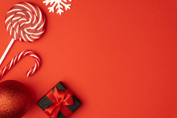 istock Christmas composition. Gift box, baubles, candy, lollipop candies, red decorations on red background. Christmas, winter, new year concept. Flat lay, top view, copy space 1185254311