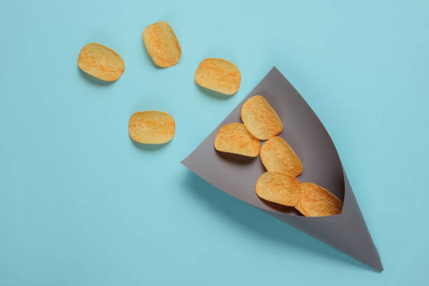 istock Chips slices in paper bag on blue background. Top view 1185254983