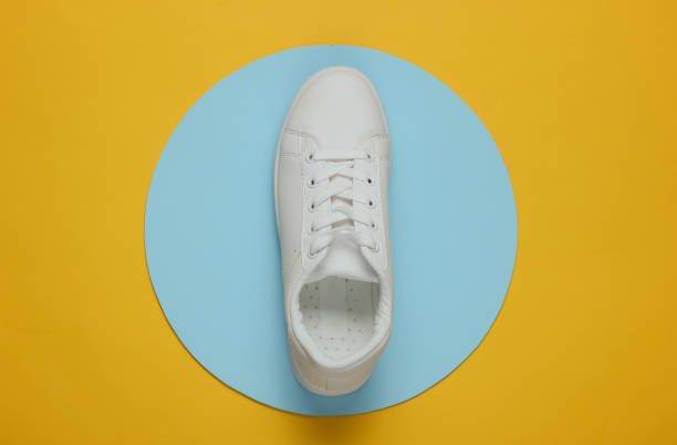 istock Stylish white sneaker on a yellow background with blue circle in the middle. Top view. Minimalism fashion still life 1185255088