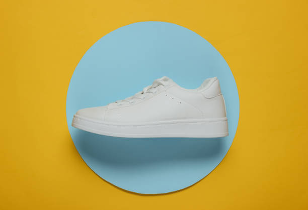 istock Stylish white sneaker on a yellow background with blue circle in the middle. Top view. Minimalism fashion still life 1185255144