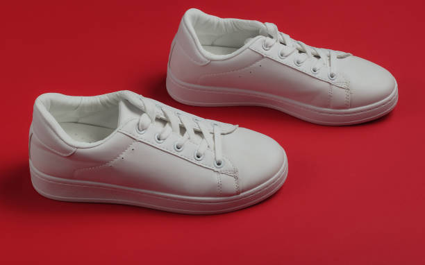 istock Stylish white sneakers on red background. Studio shot 1185255155
