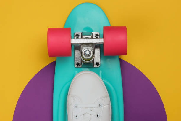 istock Stylish white sneakers with cruiser board on colored background. Summertime fun. Studio shot, top view. 1185255161