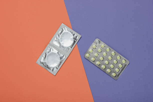 condoms dans l'empaquetage, pilules de contrôle de naissance sur un fond coloré. vue du haut. le concept de préservation sexuelle - contraceptive sex education birth control pill condom photos et images de collection