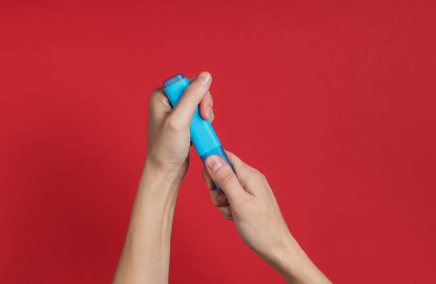 istock Female hand holds a blue felt-tip pen on red background. Top view 1185255328