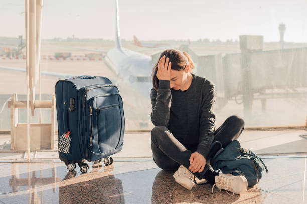 traurige (müde) frau sitzt am flughafen - verpasstes oder annulliertes flugkonzept. - airport lounge airport one person bag stock-fotos und bilder