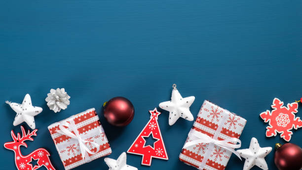 istock Flat lay Christmas red and white decorations on blue background with copy space. Top view wooden ornaments, gift boxes wrapped festive paper, stars, balls. Vintage Xmas greeting card template. 1185257089