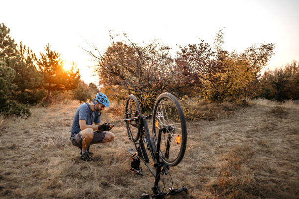 istock Mountain biker crouching on dirt road by broken bicycle 1185257411