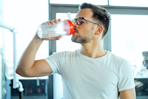 istock Man with eyeglasses drinking water in gym 1185258587