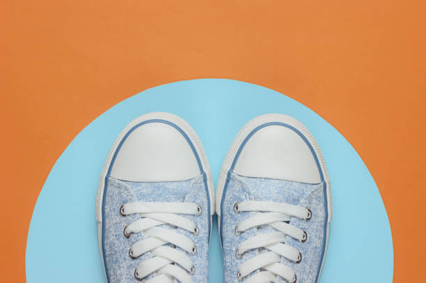 istock Stylish hipster sneakers on brown background with blue circle. Top view 1185263024
