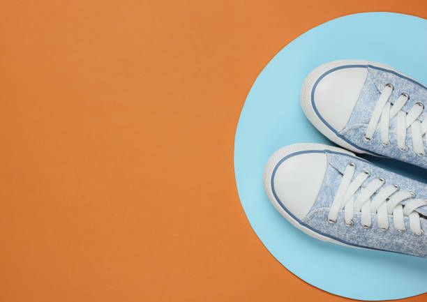 istock Stylish hipster sneakers on brown background with blue circle. Top view 1185263042