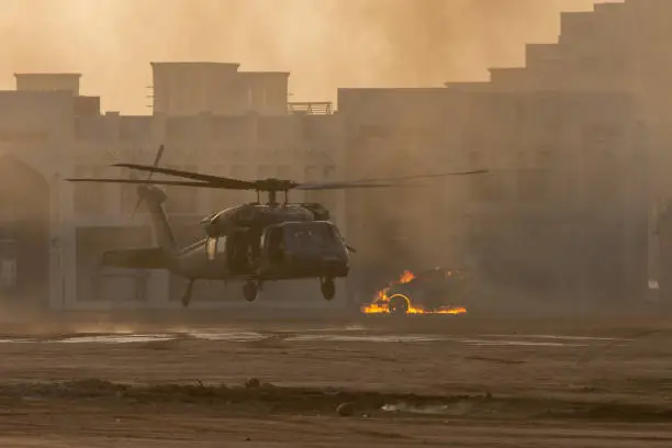 Military combat and war with helicopter landing in the chaos and destruction. Smoke and fire on the ground. Military concept of power, force, strength, air raid.