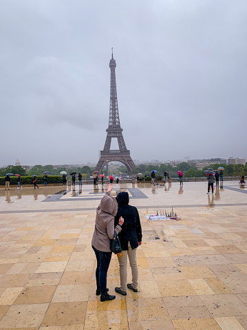 Paris, France - May 10, 2019: Tourists admiring Eiffel Tower under heavy rain, Paris, France