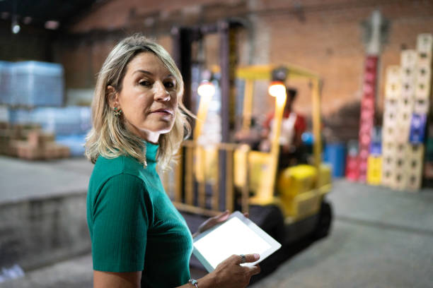 Portrait of employee holding a digital tablet at warehouse Portrait of employee holding a digital tablet at warehouse looking over shoulder stock pictures, royalty-free photos & images