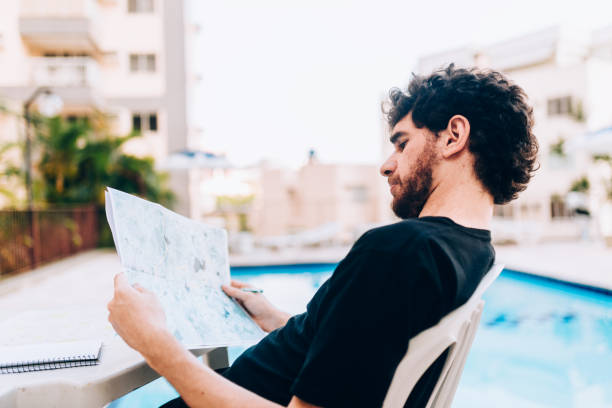 istock Young man looking at map planning the travel vacation 1185265486