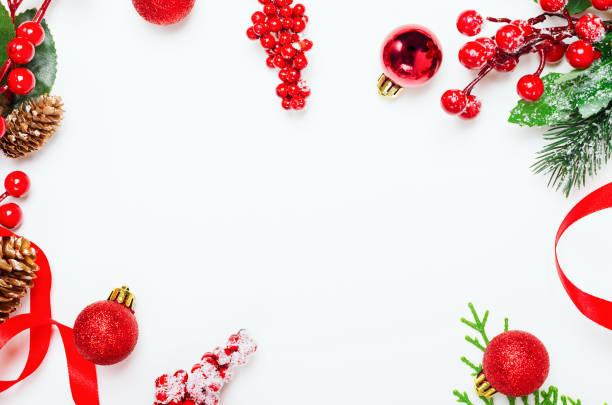 istock Holly ilex twigs and pinecones top view background. Decorative botanical frame with copyspace on white backdrop. Christmas, New Year composition with hoarfrost berries, fir branches, ribbons and toys 1185266263